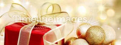 Christmas gift and baubles on golden background