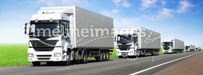Caravan of white trucks on highway under blue sky