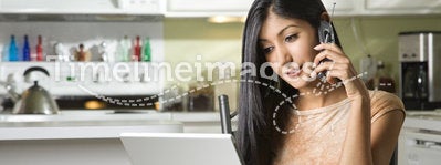 Young Woman Using Laptop and Talking on Cellphone