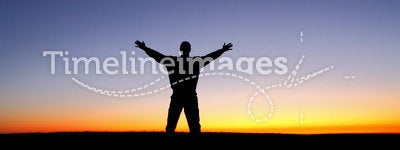 Silhouette of man with arms outstretched at sunset