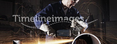 Worker cutting pipe with angle grinder.
