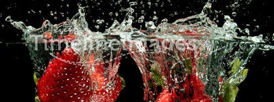 Strawberries splashing into water