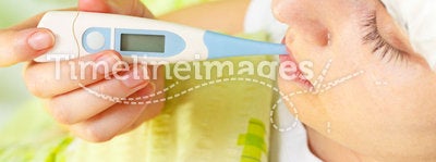 Woman being ill in bed and measuring temperature