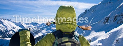 Girl with snowboard agaist the mountains
