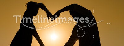 Sillhouette loving couple at sunset with heart