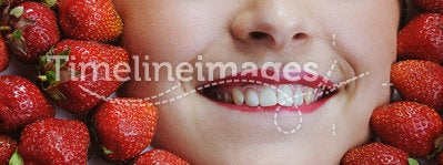 Young beautiful woman with white teeth closing her eyes on strawberries background