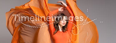 Beautiful woman in long orange dress posing dramatic