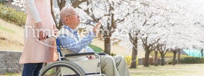 Asian senior man sitting on a wheelchair with caregiver pointing