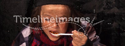 Poor beggar child eating charity food
