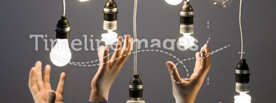 Hands reaching for light bulbs