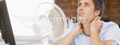 Businessman in office with computer and fan