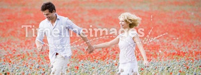 Couple walking in poppy field holding hands