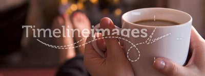 Feet warming at a fireplace with coffee