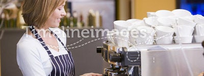 Woman making coffee in restaurant smiling