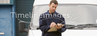 Delivery person standing with van writing