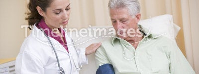Doctor checking man's blood pressure in exam room