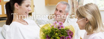 Young Girl Giving Flowers To Mother In Hospital