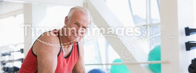 Man Using Hand Weights On Swiss Ball At Gym