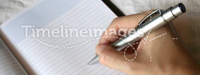 Hand holding pen writing on note book