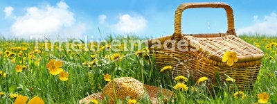 Summer picnic basket with straw hat in a field