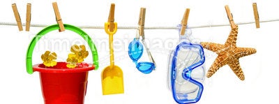 Child's summer toys on clothesline against white